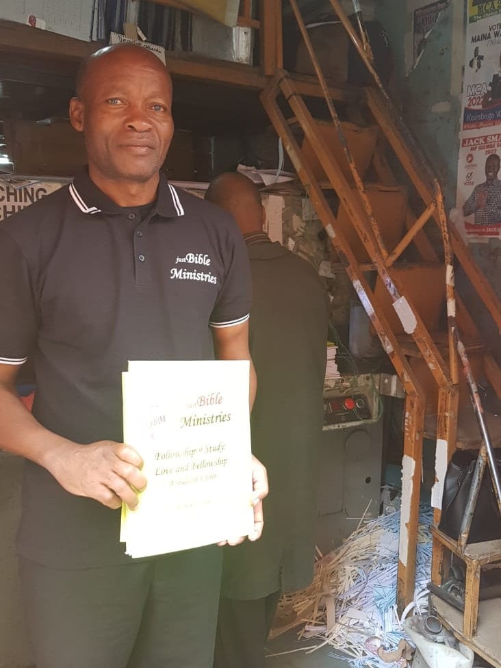 Pastor Maurice with 1 John notebooks, 2022.