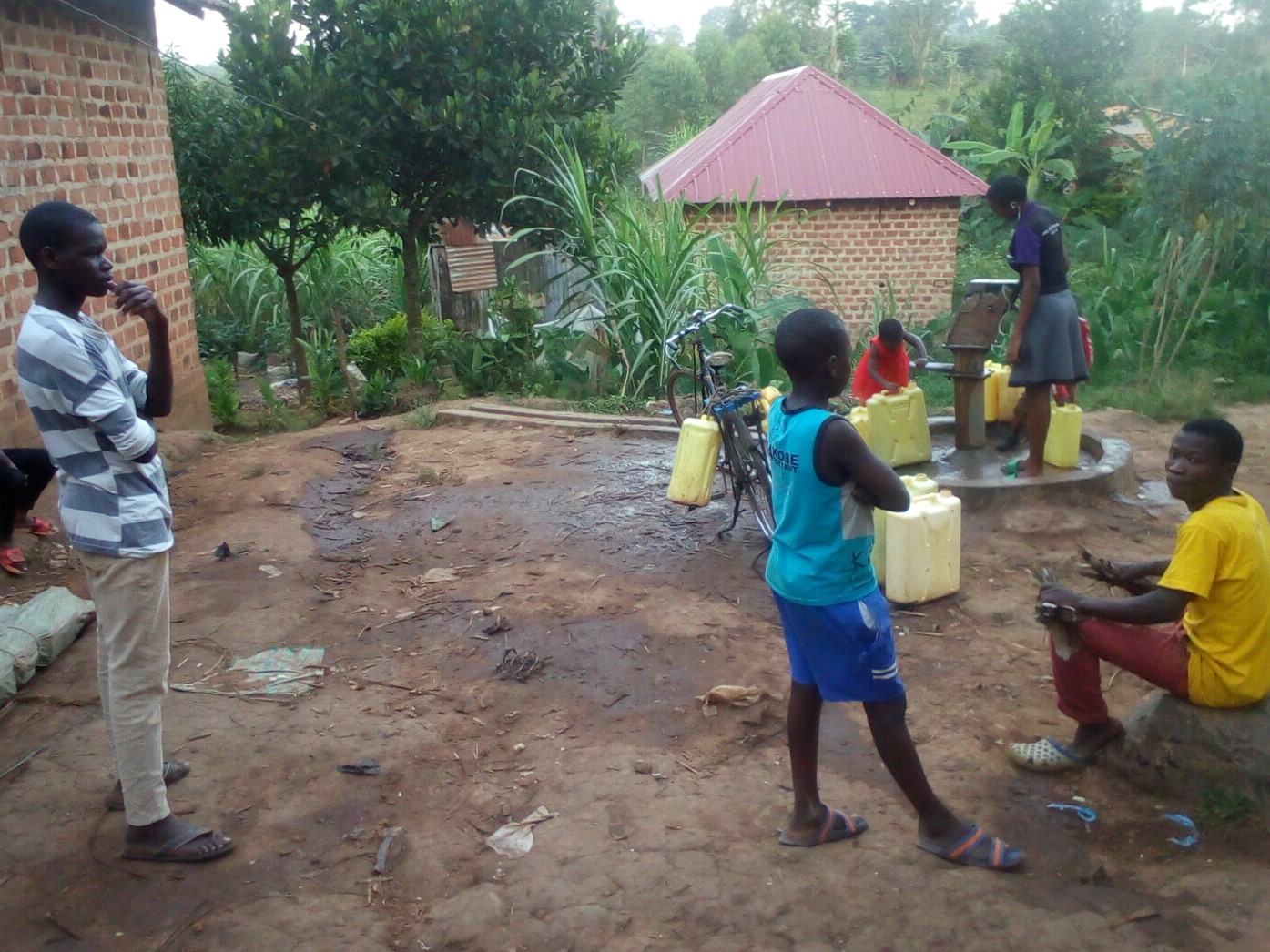 Neighbors drawing water from the completed Grace well.