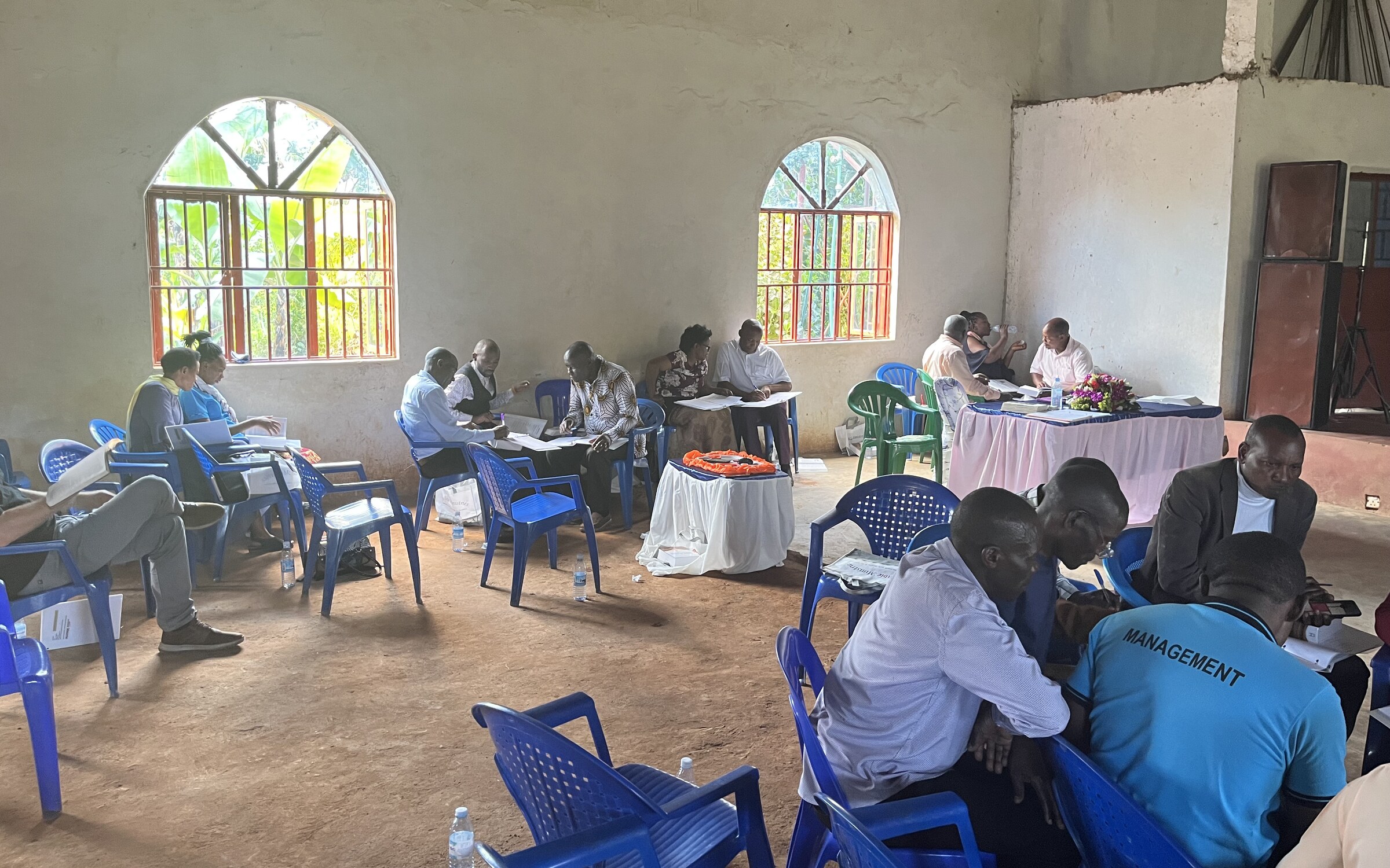 Pastors in small groups around tables, working a passage together at a Bible Study Techniques workshop.