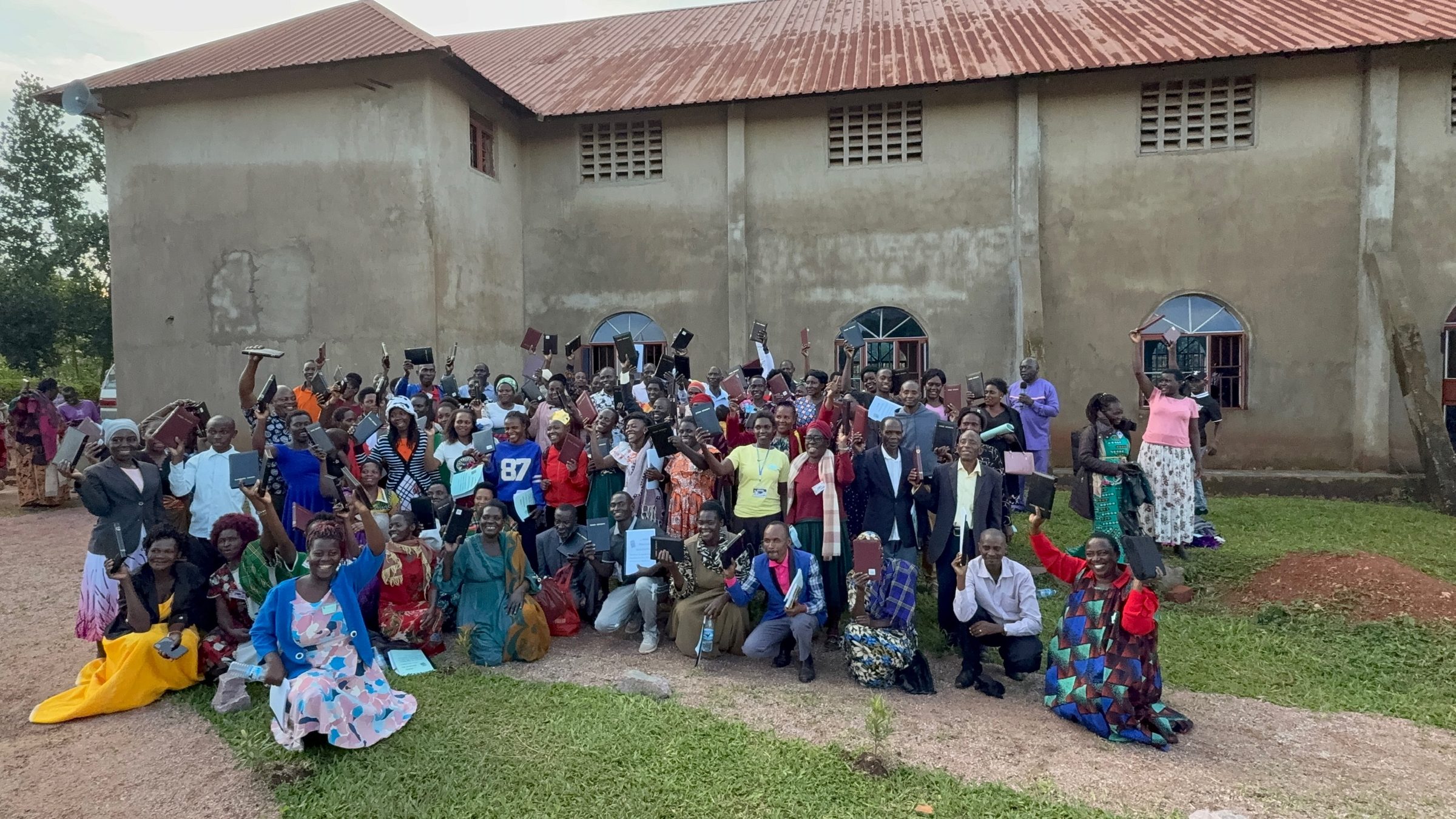 Congregation with Bibles raised outside the Zion Community Center in Uganda.