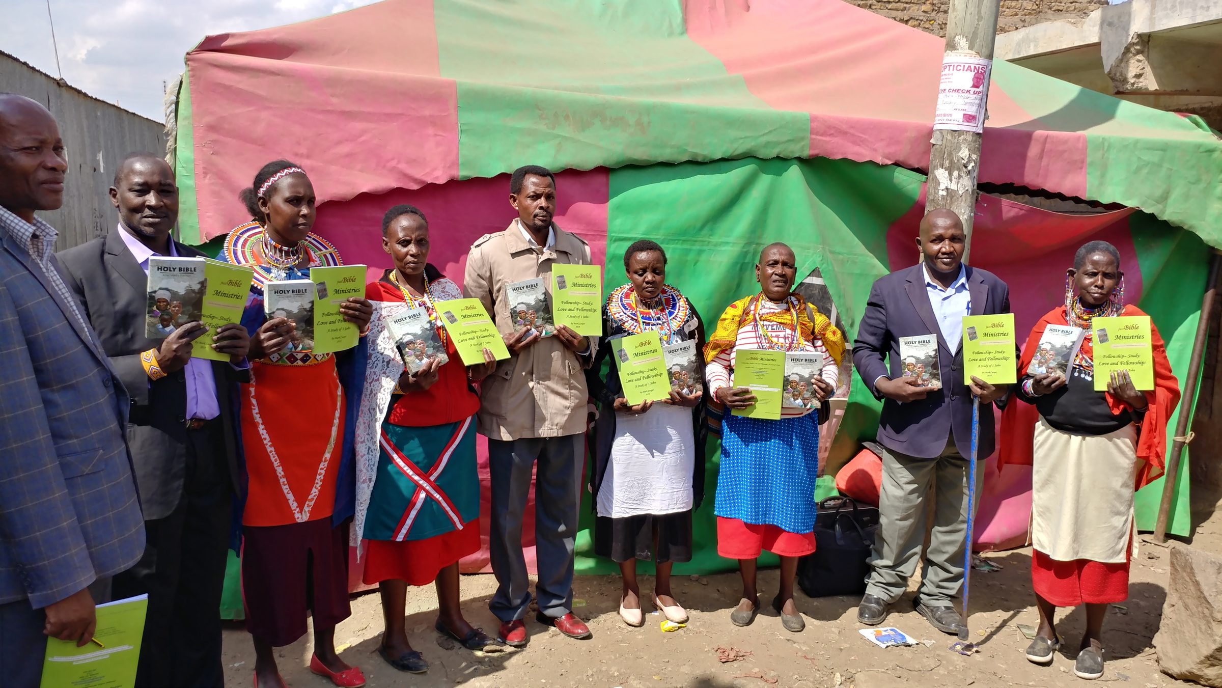 Men and women holding the Bibles and workbooks they received.