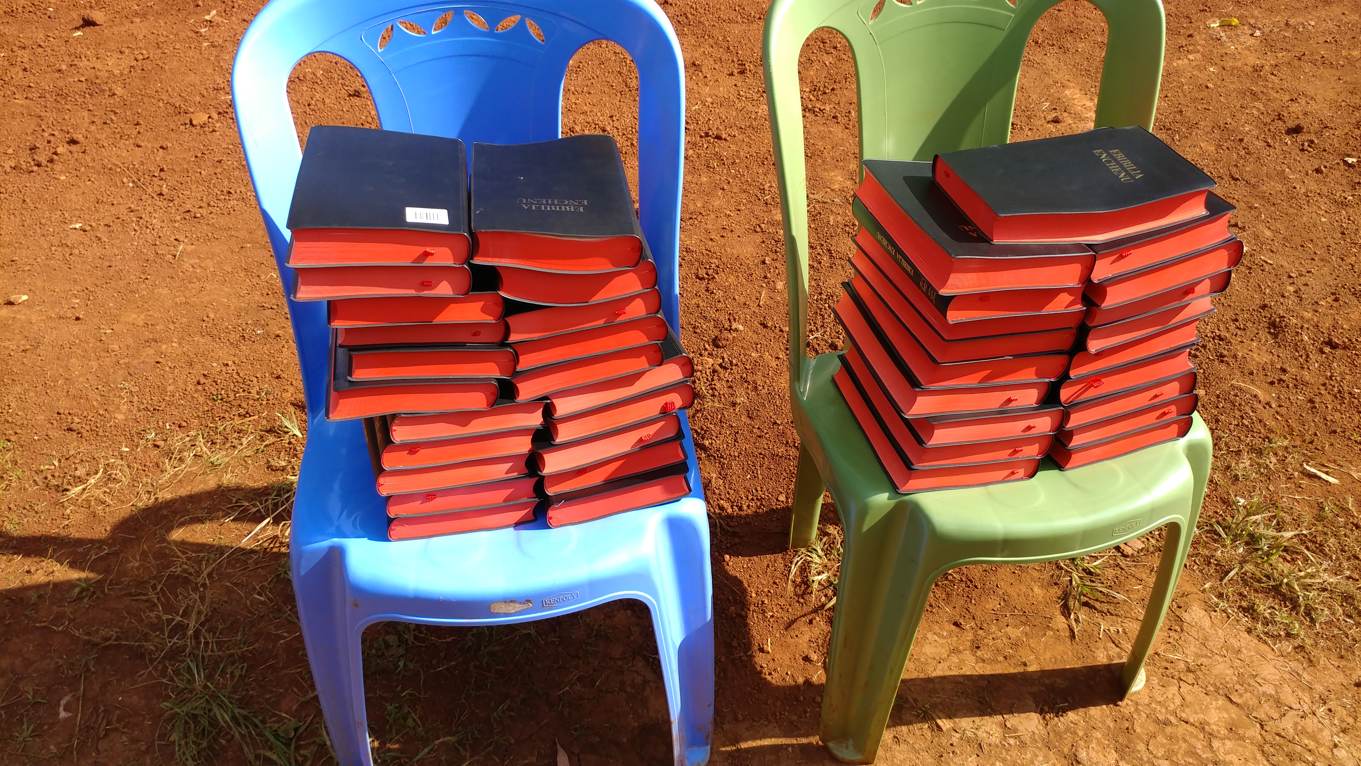 Stacks of black Bibles with red page edges on plastic chairs at a Christian Restoration Church Partner Symposium, July 2019.