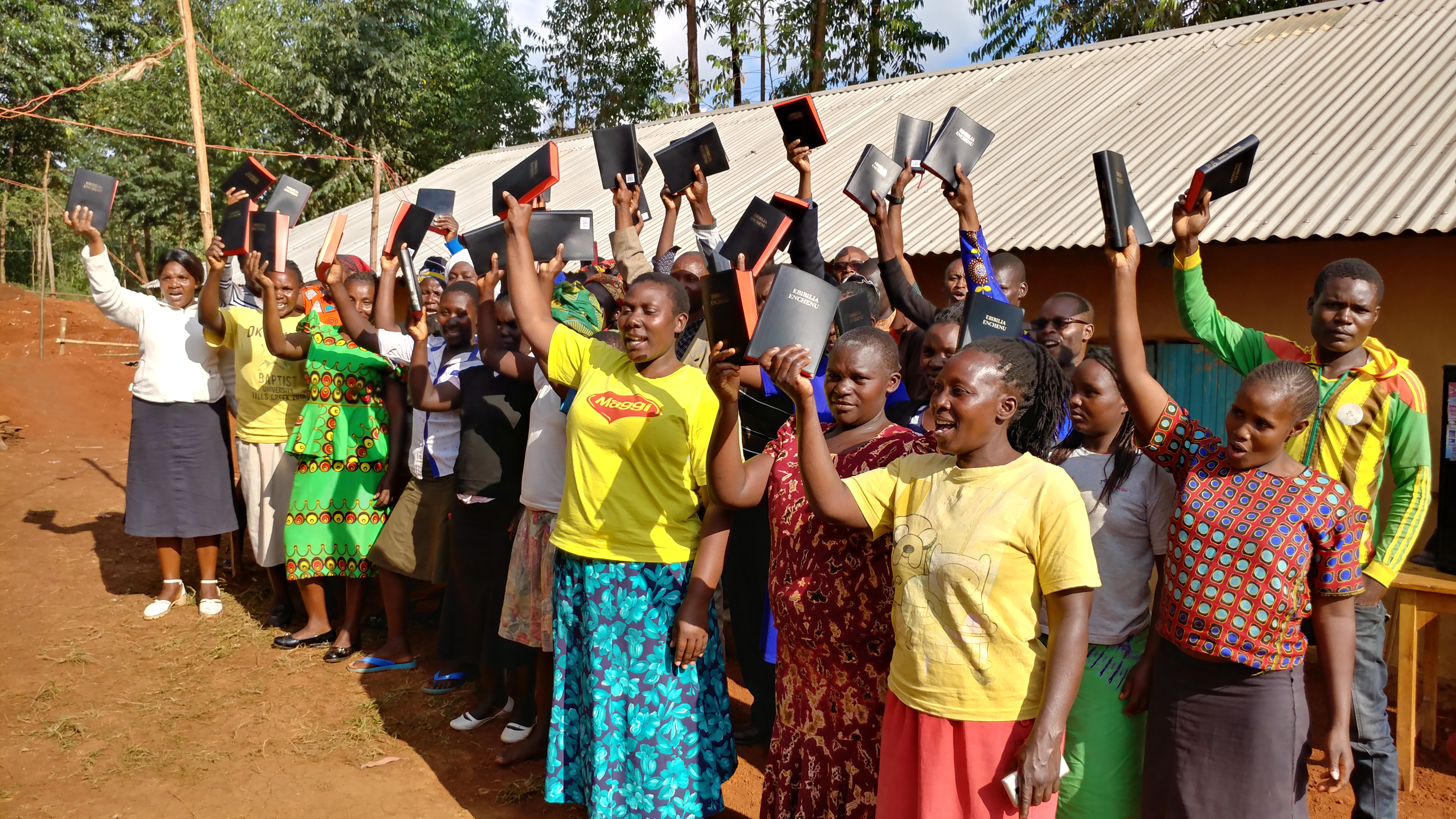 Congregation raising Bibles after a Partner Symposium with Christian Restoration Church, July 2019.