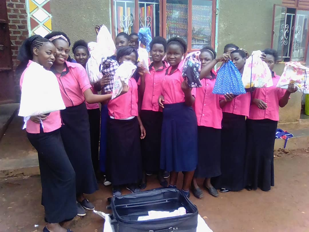 VHC-GCC girls in pink uniforms holding donated kits and dresses.
