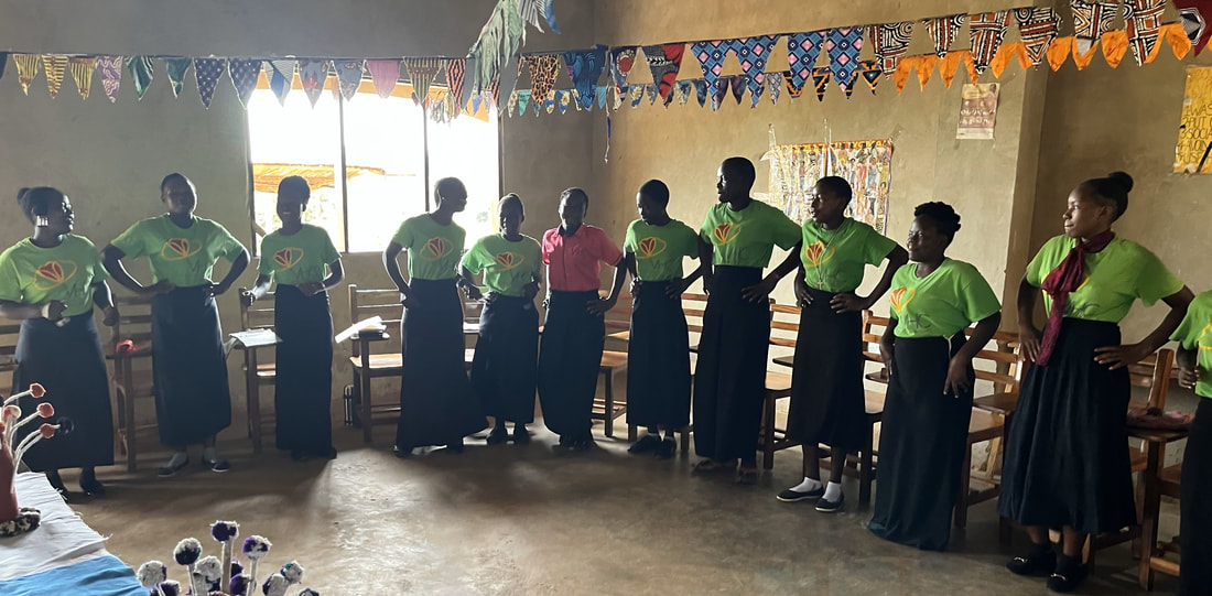 Girls in green Volunteer Heart shirts lined up along the wall of their classroom in Kikyusa.
