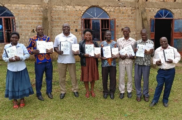 Eight pastors holding workbooks, commissioned.